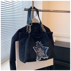 Detail of star denim patch and gold chain strap on black frosted tote bag