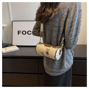 Vue détaillée du sac cylindrique beige avec imprimés ours porté par un mannequin