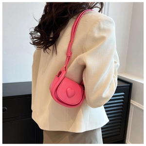 Detailed view of mini pink crossbody bag with heart ornament on a fashion model