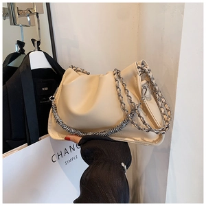 Detailed macro view of beige cloud bag with elegant silver metallic chain texture