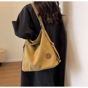 Détail de la bandoulière et du patch cuir sur le sac hobo en toile jaune moutarde