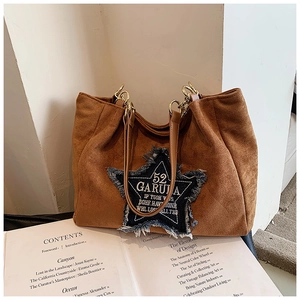 Detail of brown suede tote bag with blue denim star patch and gold metal hardware