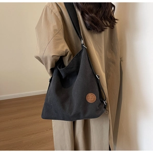 Détail du sac cabas en toile noire avec patch en cuir marron et large bandoulière