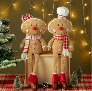 Close-up of plush Christmas gingerbread dolls with scarves on a wooden stand