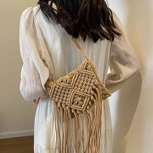 Handmade woven crossbody bag with fringe details and braided strap on model's back