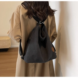 Vue détaillée d'un sac à dos noir en toile avec grande capacité et patch logo en cuir brun
