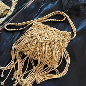 Beige macramé straw crossbody bag with handmade fringe details for summer beach style