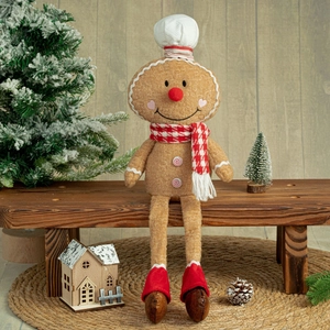 Macro shot of long-legged plush gingerbread doll sitting on a wooden bench with pine cones