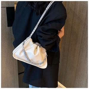 Detail of cream cloud bag with silver chain and woven strap on a black blazer