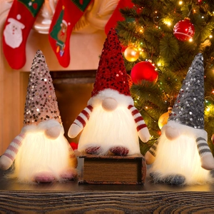 Three glowing Christmas gnomes with sequined hats and LED warm lights on a fireplace