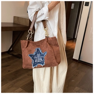 Close-up of brown suede tote bag with denim star patch and gold chain strap detail