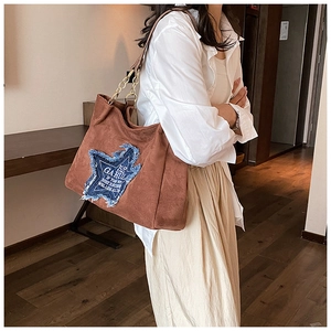 Detail of large brown tote bag with star patchwork and metal chain shoulder strap