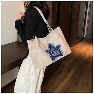 Detail shot of large tote bag featuring blue star patch and chain leather strap