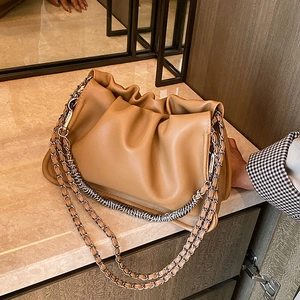 Minimalist camel leather cloud bag with chunky silver chain on marble surface