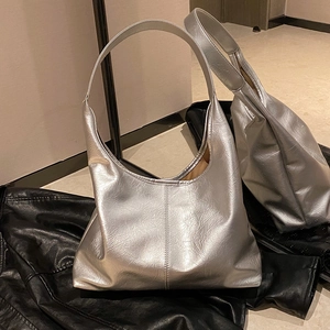Sac hobo argenté métallisé avec texture plissée posé sur une veste en cuir noir chic