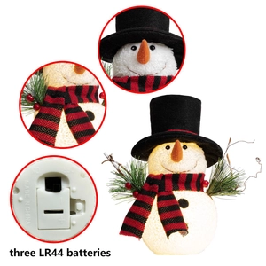 Detail van pluchen kerstsneeuwpop met takarmen, rode bessen en het batterijcompartiment