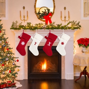 Detail of knitted Christmas stockings with snowflake embroidery and pom-poms on mantel
