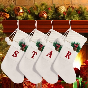 Detail of 4 white knitted Christmas stockings with STAR letters and natural pine decor