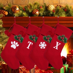 Detail of red knit Christmas stockings with plush pom poms and letter felt patches
