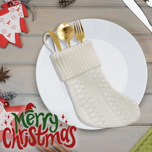 Knitted Christmas stocking cutlery holder with gold utensils on a festive dinner table