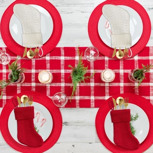 Knitted Christmas stocking cutlery holders in red and white on a rustic dining table