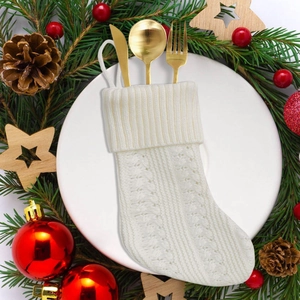 White cable knit Christmas stocking cutlery holder with golden utensils on a plate