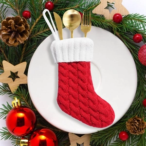 Portaposate a calza di Natale rossa lavorata a maglia su un piatto festivo decorato