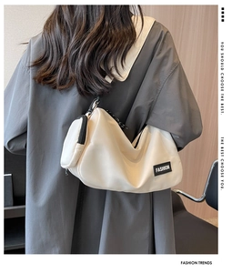 Detailed side view of off-white nylon crossbody bag with zipper pocket and fashion patch