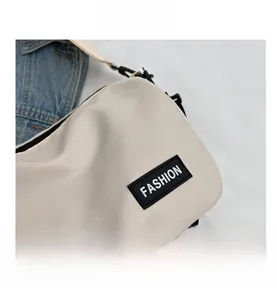 Detail of beige nylon crossbody bag with black FASHION rubber patch and woven strap