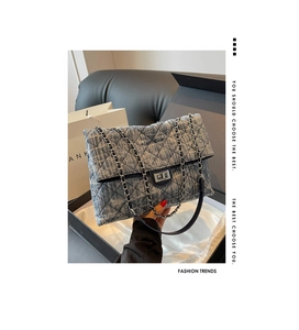 Detailed close-up of grey tweed quilted shoulder bag with silver chain and twist lock