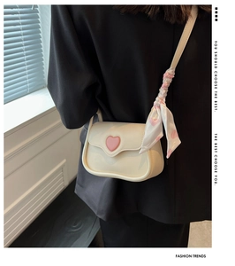 Detail of cream shoulder bag with pink heart clasp and matching silk scarf accessory