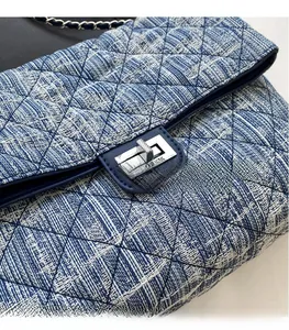 Detail of blue denim quilted pattern with classic silver rectangular metal lock