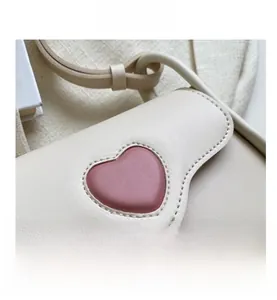 Close-up of beige PU leather bag featuring a pink heart patch and fine stitching details