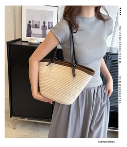 Detail of hand-woven tote bag showing beige rope texture and brown braided trim edge