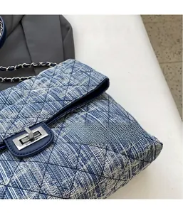 Detailed macro view of quilted denim texture and silver square turn-lock on the shoulder bag