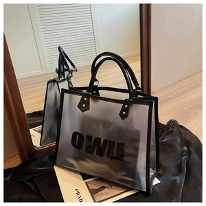 Detalle del bolso tote transparente con letras OWU y ribete de cuero negro con remaches