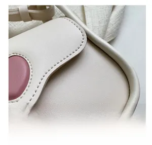 Close-up of precise stitching and premium leather texture on a cream crossbody bag