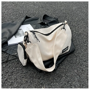 Detail of a creamy white nylon shoulder bag with a fashion tag and mini pouch