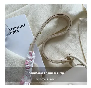 Detail of adjustable cream shoulder strap with gold studs and decorative ribbon