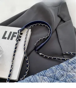 Close-up of a silver chain strap with blue leather detail on a denim quilted bag
