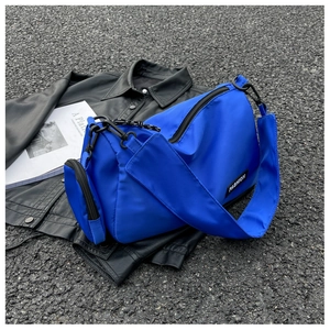Detail view of bright blue nylon crossbody bag with detachable small pouch on shoulder strap