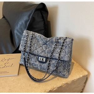 Close-up of blue tweed diamond quilted bag with silver chain and metal rotary lock
