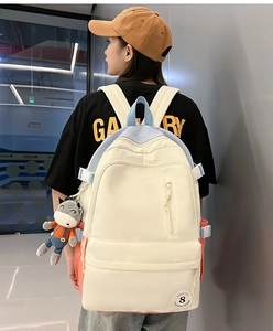 Close-up of casual cream backpack with blue and pink accents and plush charm