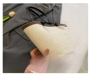 Detail of a cream woven tote bag with contrast stitching and slim leather handles