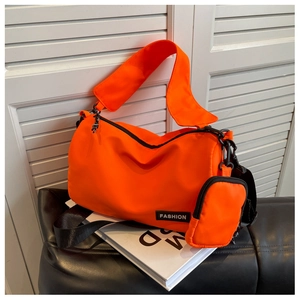 Detail of bright orange nylon crossbody bag featuring detachable mini pouch and FASHION label