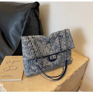 Detail of blue and white tweed crossbody bag with silver chain strap and metal lock