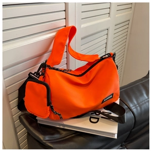 Detail of orange nylon pillow bag featuring fashion label and detachable mini pouch
