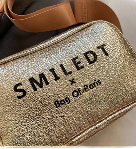 Close-up of golden cracked texture bag with wide nylon strap and printed logo detail