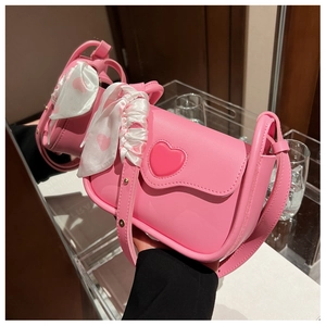 Close-up of pink crossbody bag with 3D heart detail and heart-patterned silk scarf handle