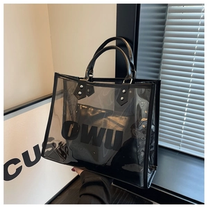 Detalle de bolso tote de PVC negro transparente con estuche de cuero interior y logo OWU